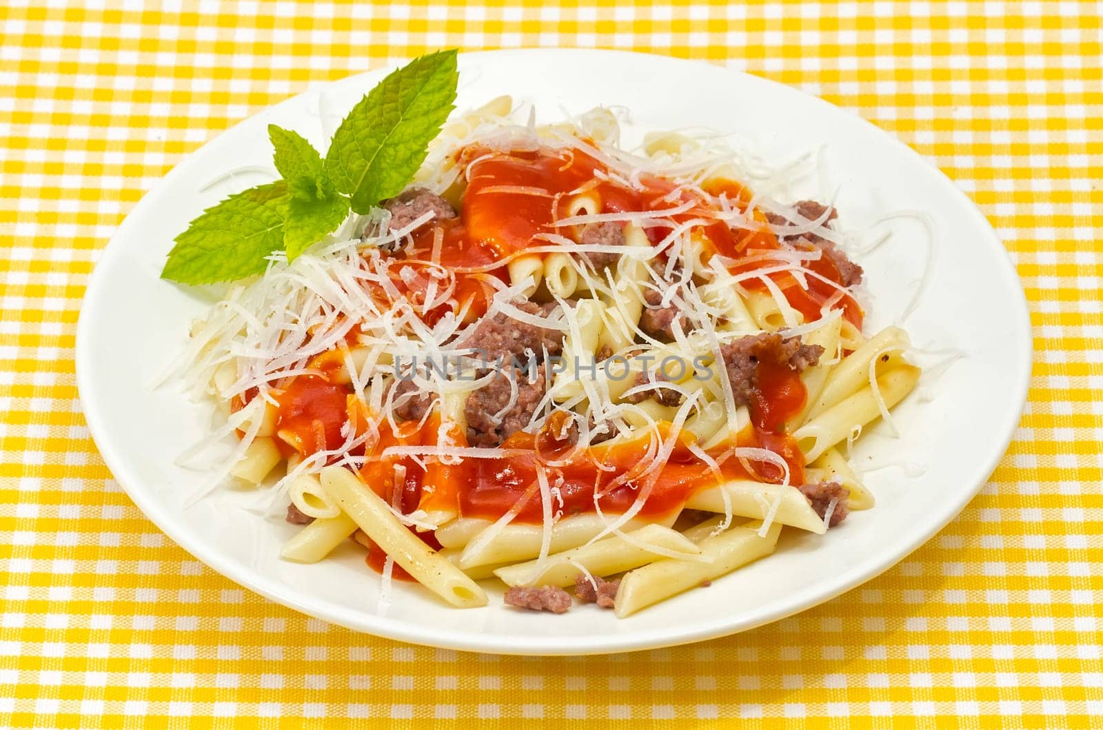 Traditional Italian macaroni pasta with tomato and grated cheese adorned with mint