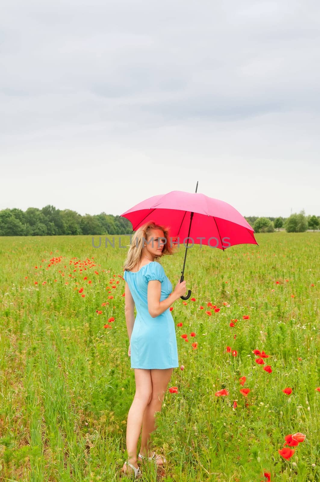 Woman with umbrella in poppy field