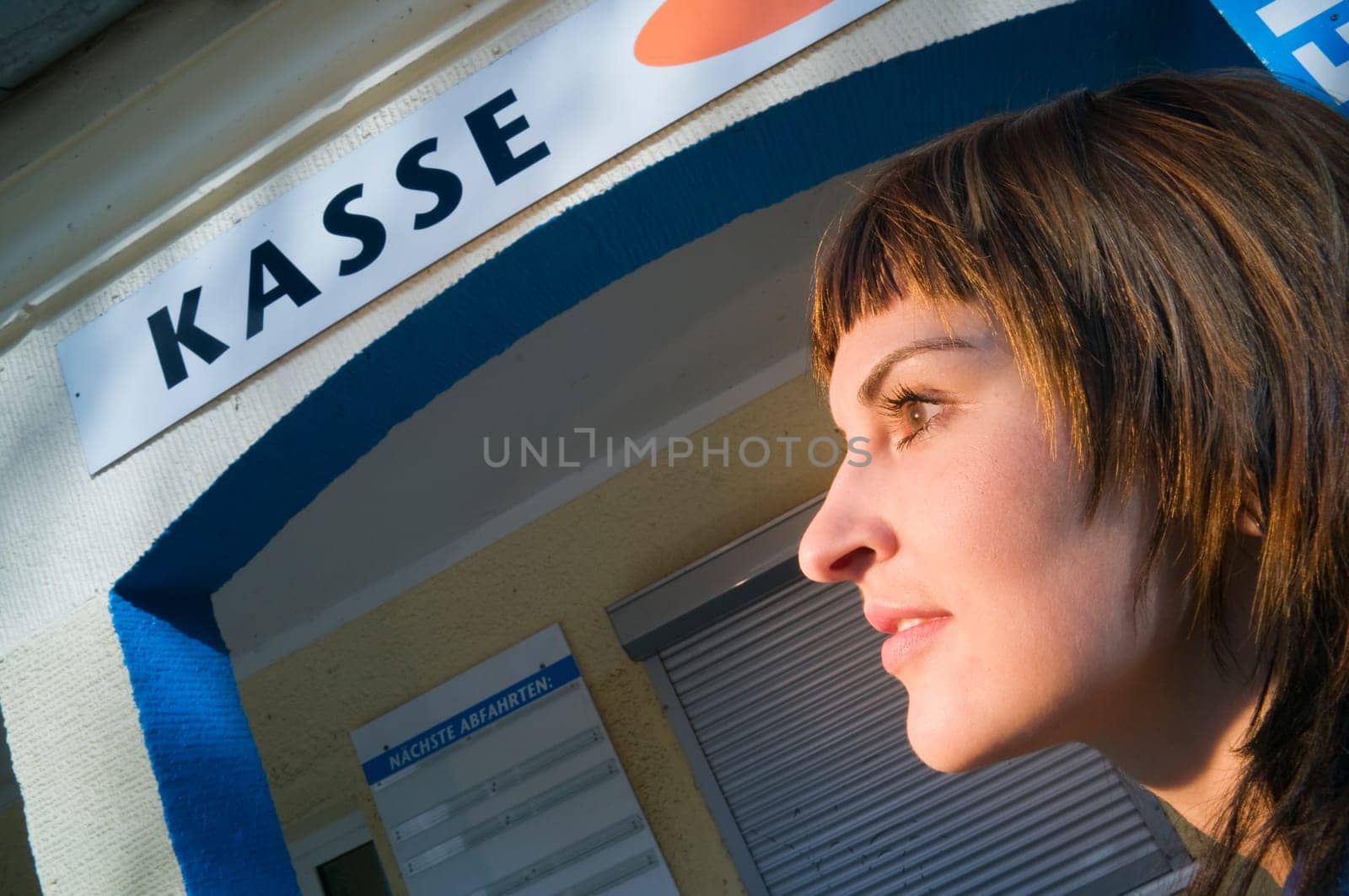 Head and shoulders shot of a young brunette woman in a lower view and a checkout sign in the background