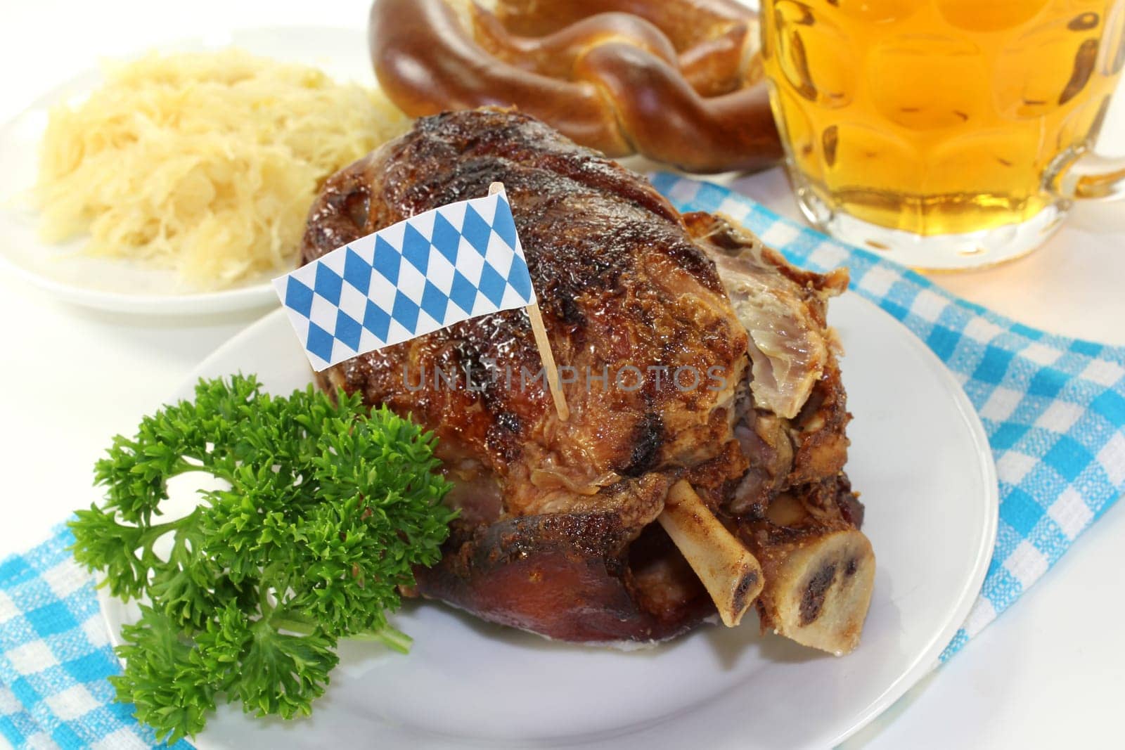 a grilled knuckle with pretzels and parsley against a white background
