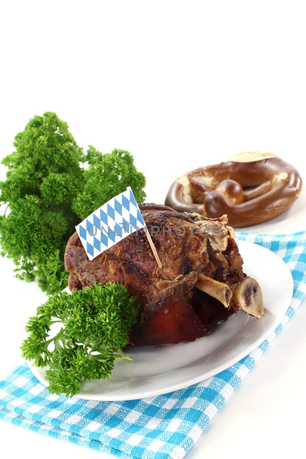 a grilled knuckle with pretzels and parsley against a white background
