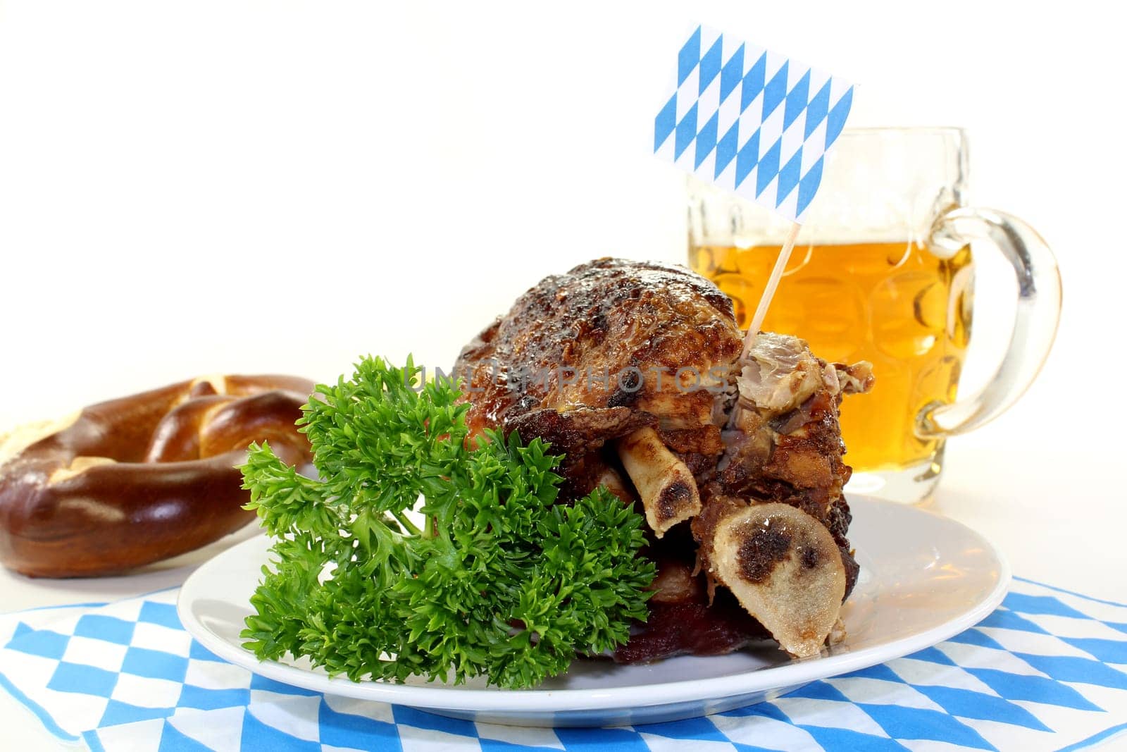 a grilled knuckle with pretzels and parsley against a white background