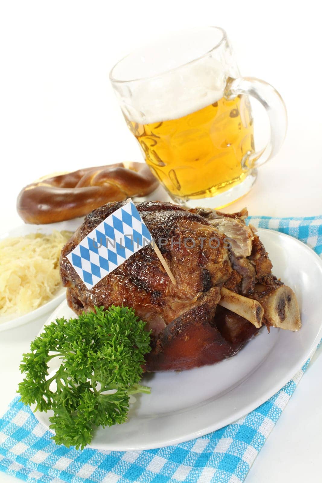 a grilled knuckle with pretzels and parsley against a white background