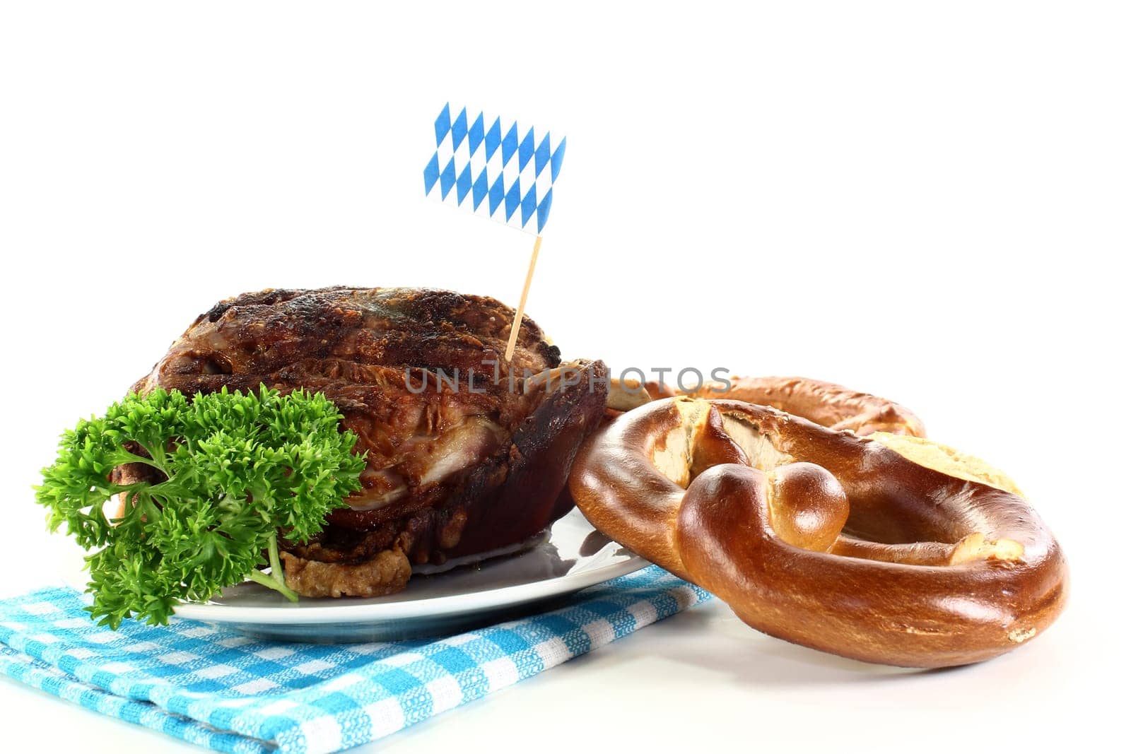 a grilled knuckle with pretzels and parsley against a white background