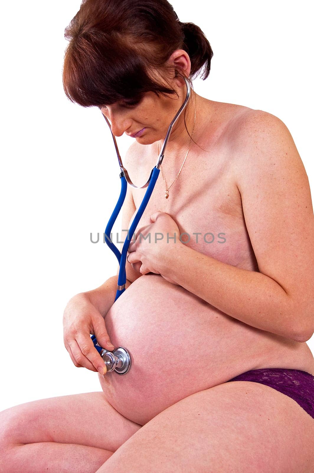 Pregnant woman listening through a stethoscope beating hearts of their baby