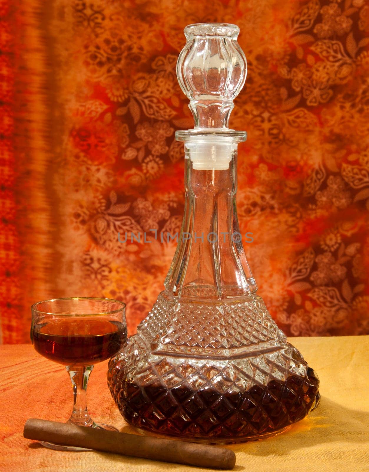 Glass and bottle of brandy with orange gradient background