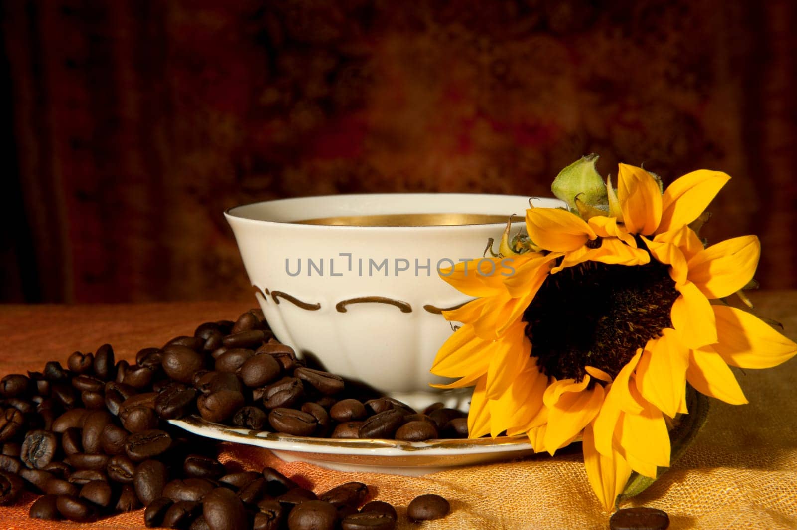 cup with coffee beans and sunflowers on a colored background