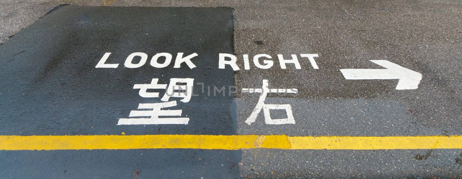 "look right"" sign on a street in hong kong, advising safety for pedestrians"