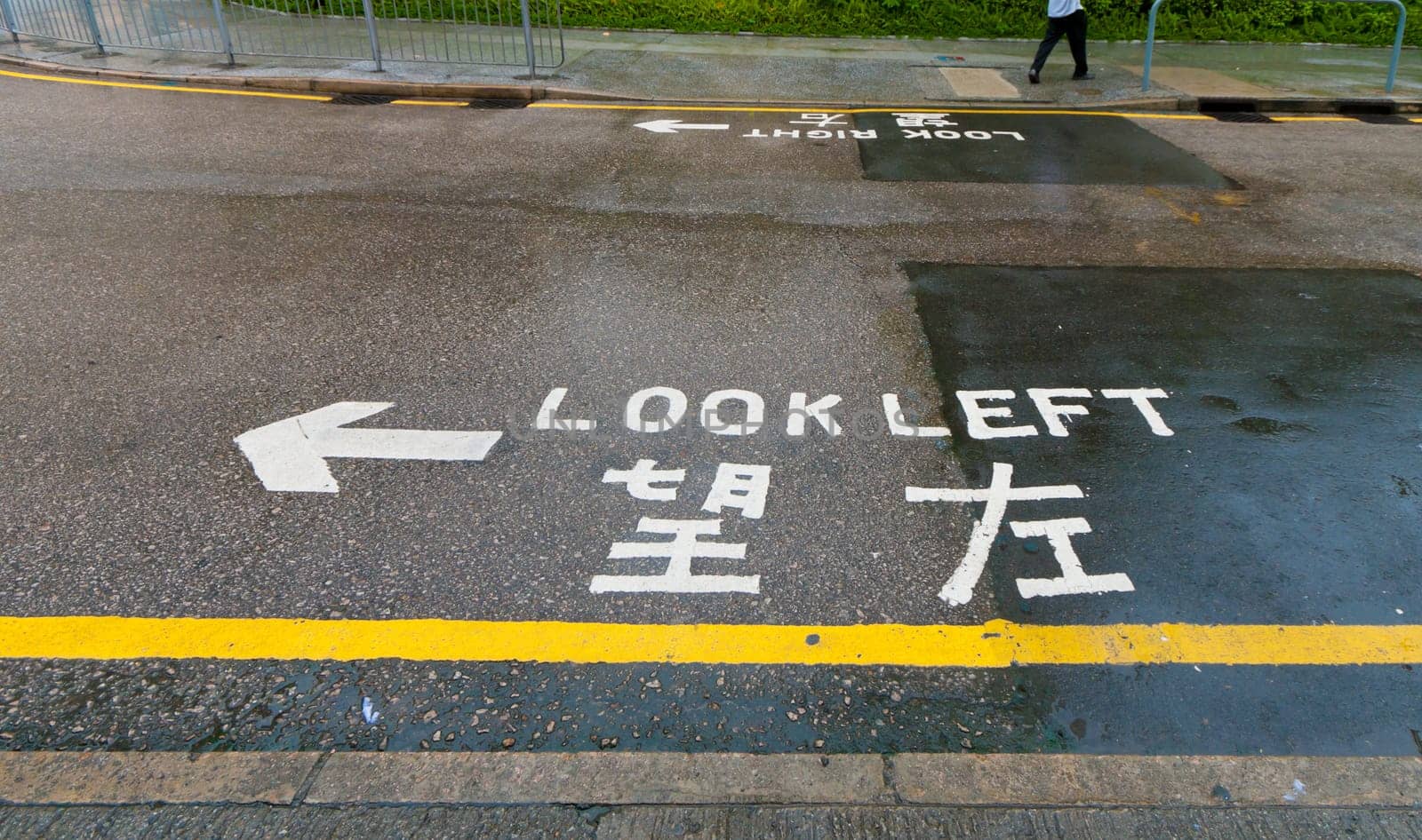 "look left"" sign on a street in hong kong, advising safety for pedestrians"