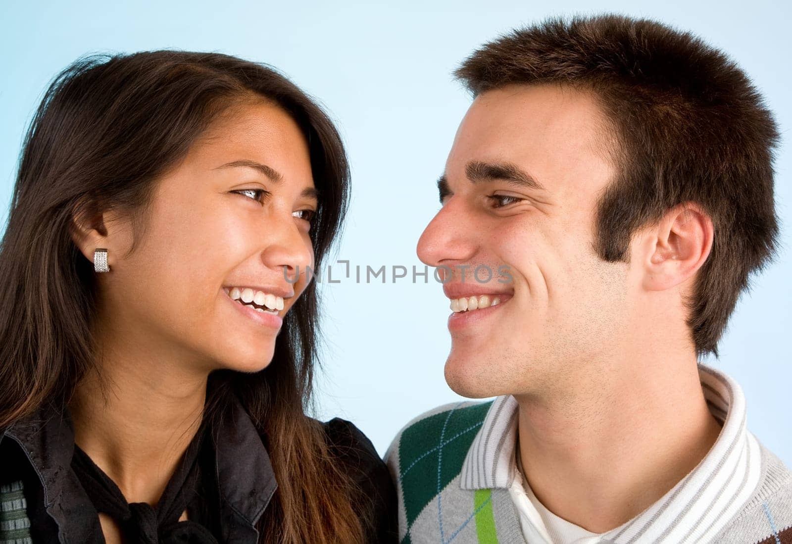 A young couple are laughing while looking at each other.