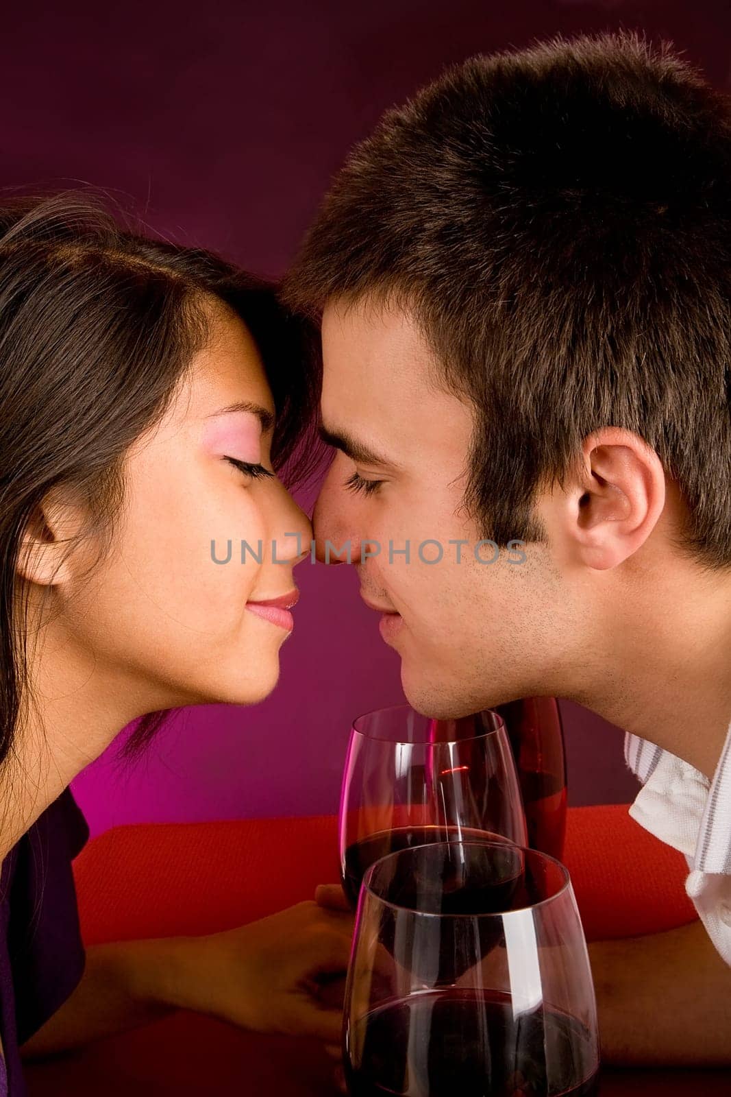 Couple sitting at a table drinking wine and getting close.