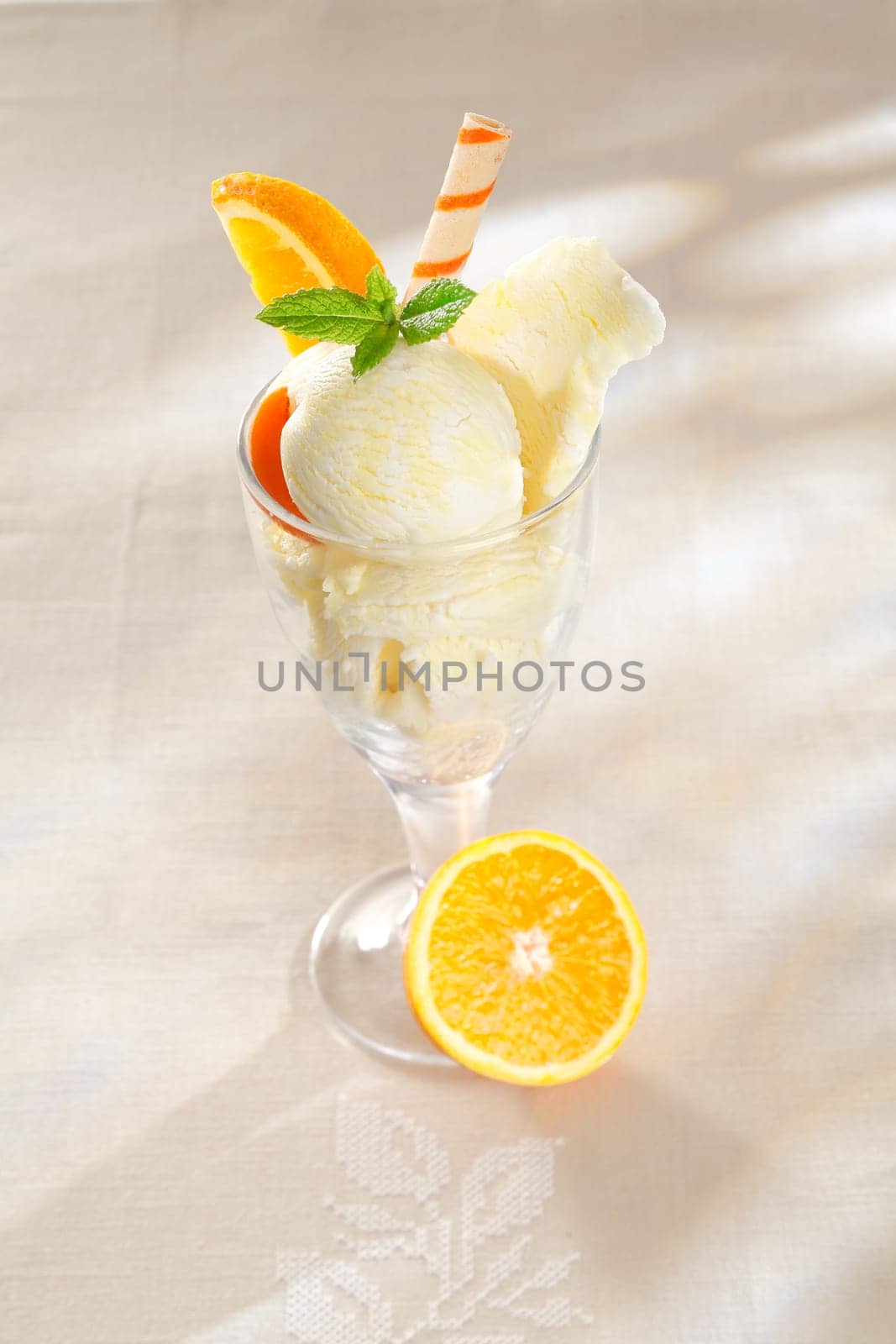 Fresh fruity orange flavoured citrus icecream in a tall parfait glass with sliced oranges and a spiral wafer