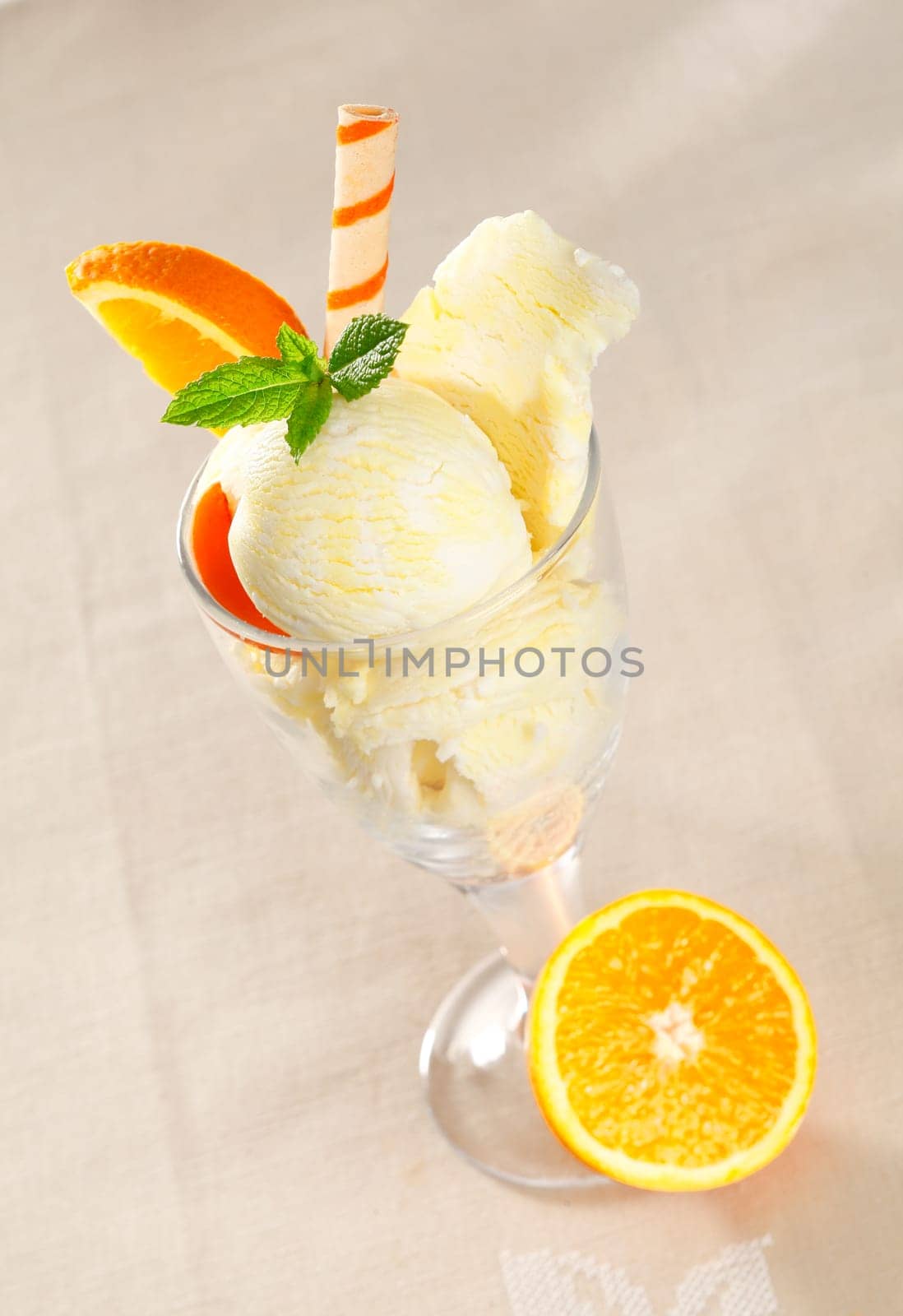 Colourful tropical icecream dessert with fresh orange slices and a spiral wafer biscuit
