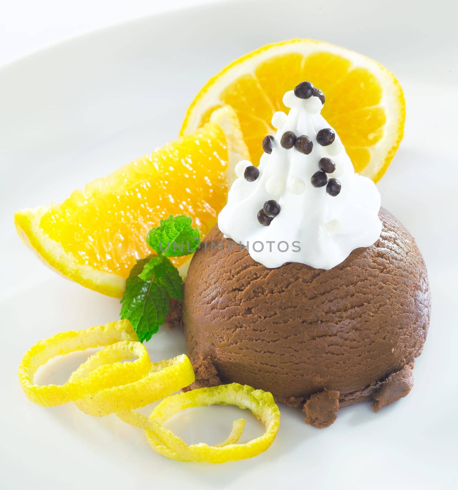 Gourmet chocolate icecream dessert topped with whipped cream and served with orange slices and zest
