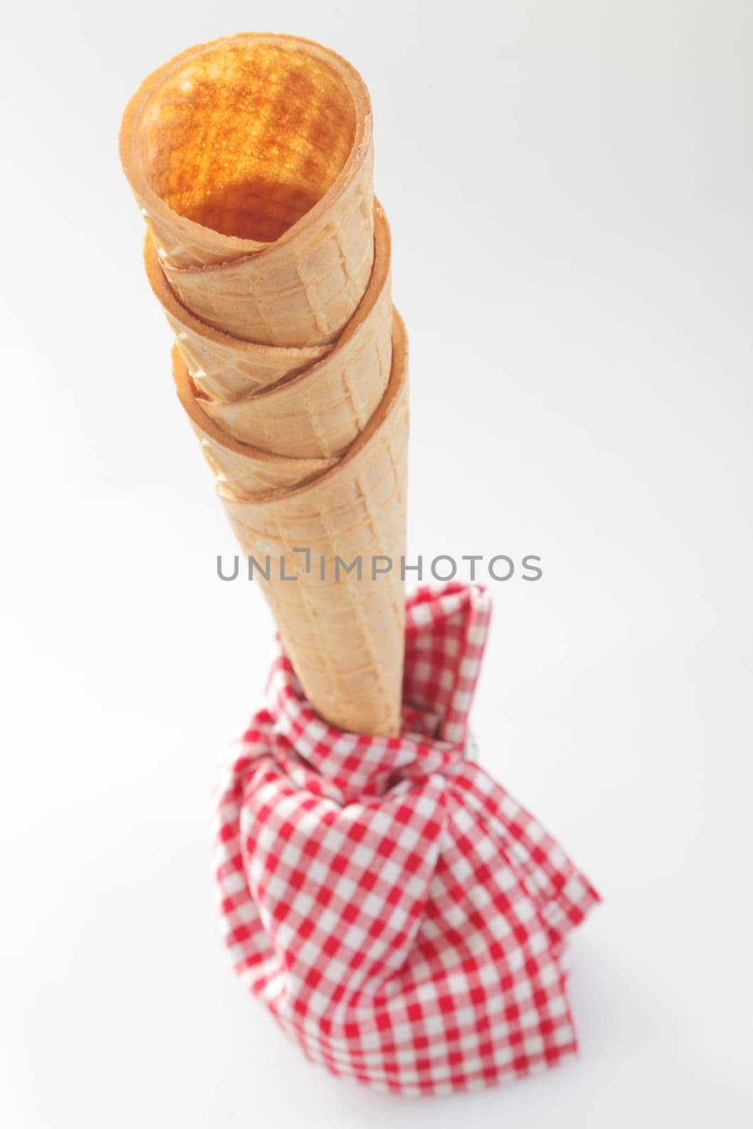 High angle view of a stack of crisp empty ice-cream cones with a red and white checkered napkin