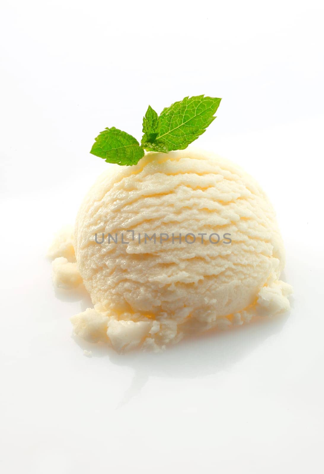 Scoop of vanilla ice-cream topped with fresh green mint leaves on a white backgound