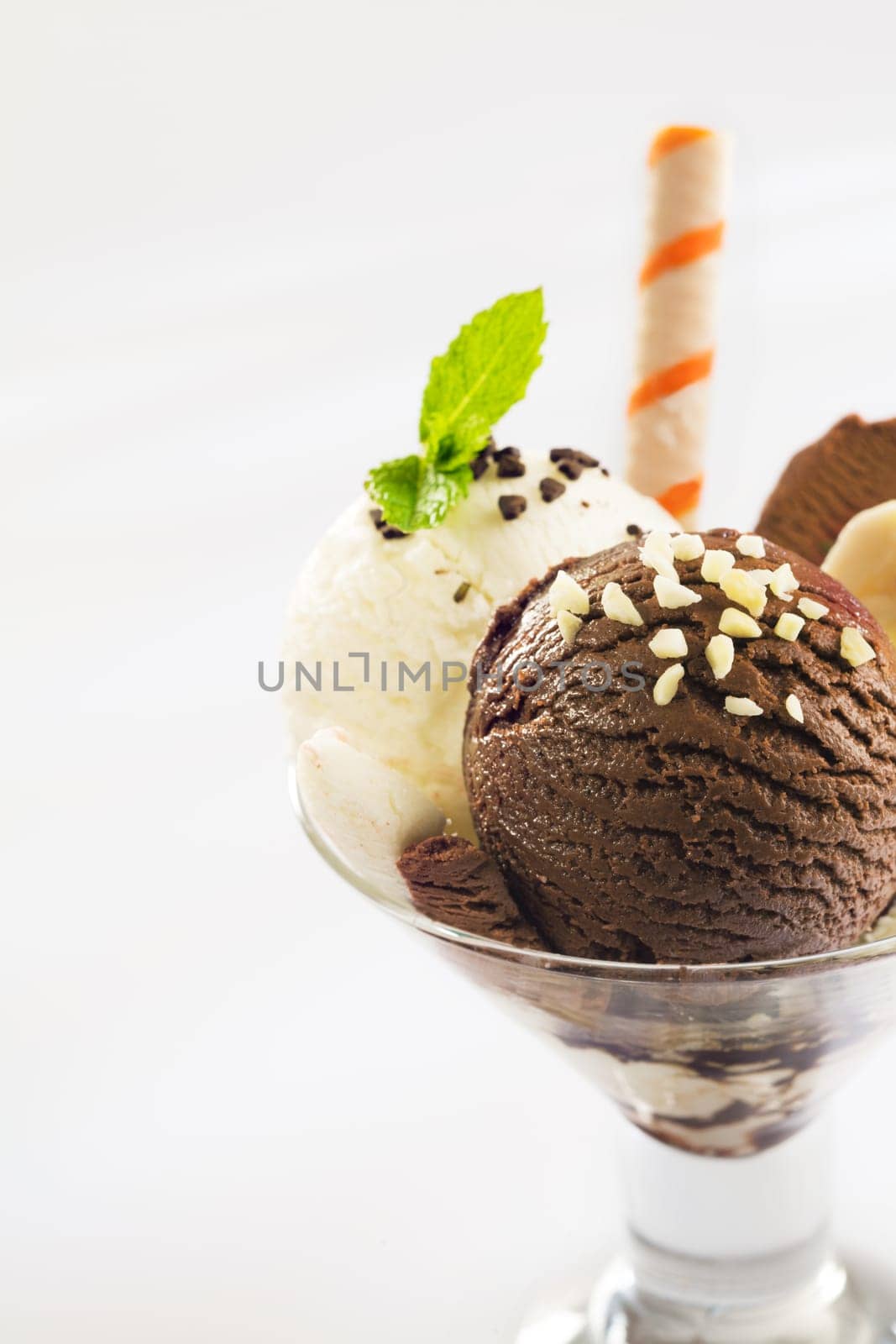 Balls of chocolate and vanilla ice-cream topped with chopped nuts in a conical glass parfait dish