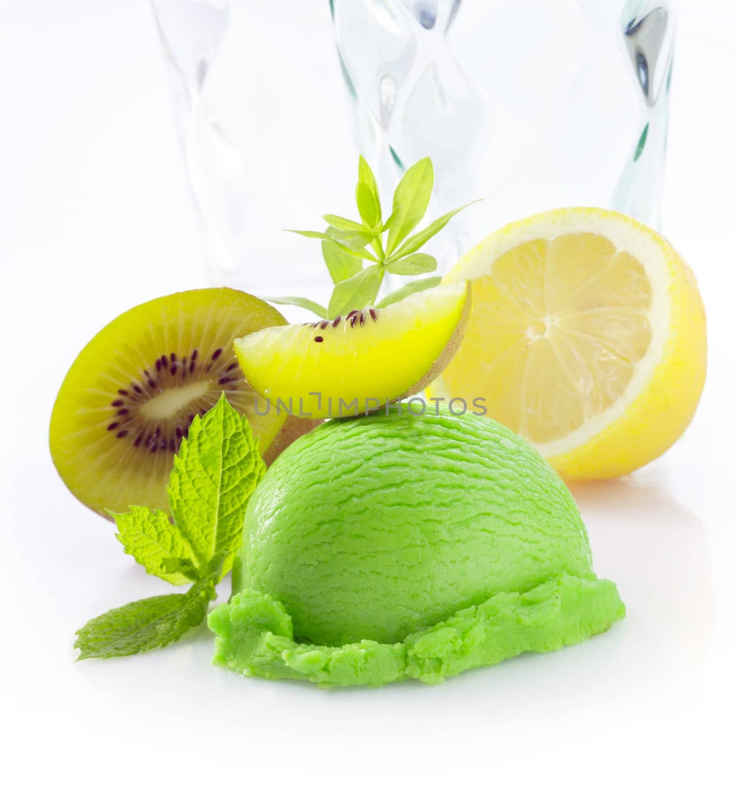 Creamy green tropical kiwi fruit icecream with fresh sliced kiwi fruit and lemon on a white background