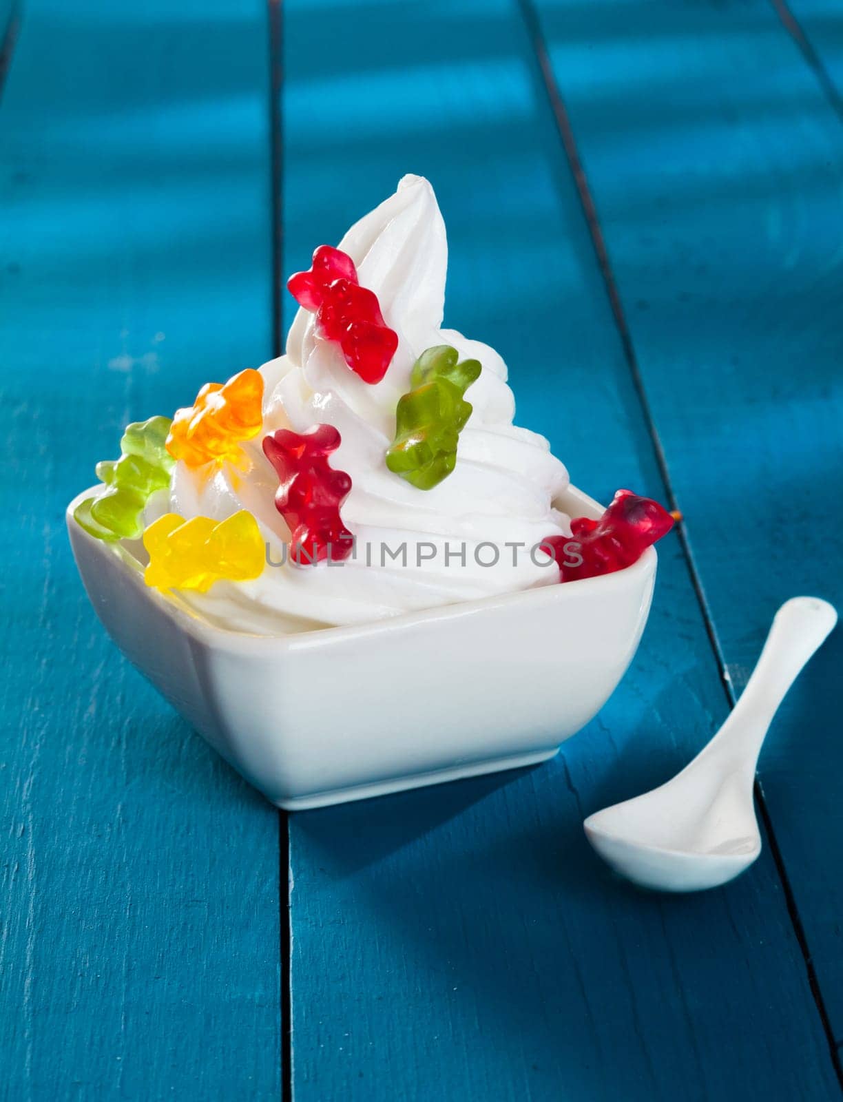 Funny Frozen Yogurt with gummi bears as topping on a wooden blue background