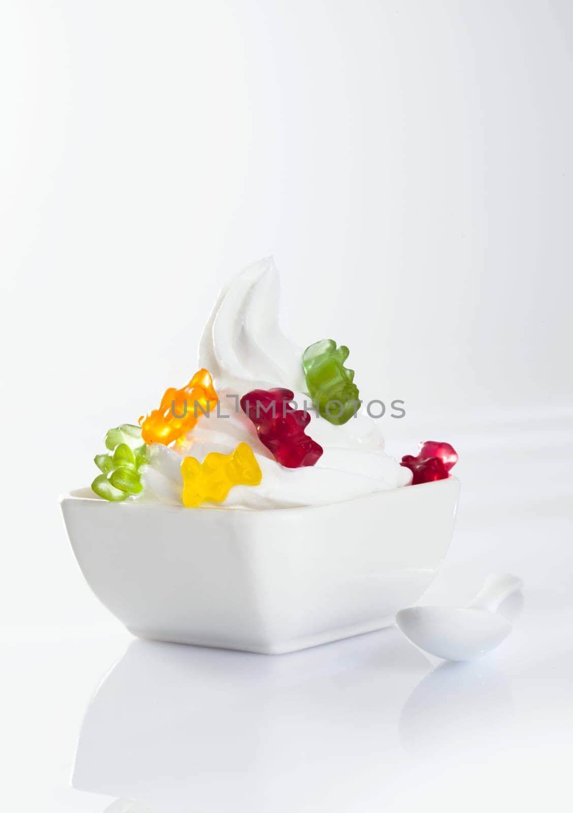 Stylish frozen yoghurt with jellybaby topping isolated on white background