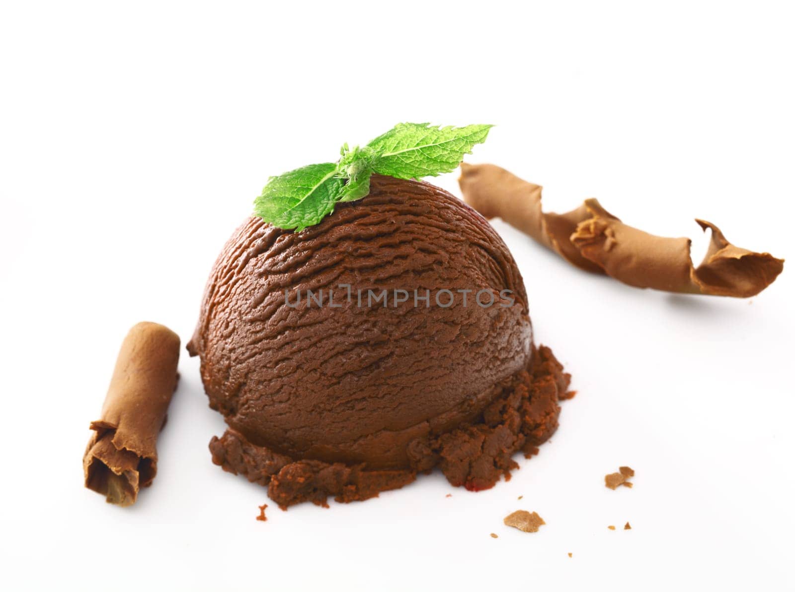 Scoop of rich creamy chocolate icecream dessert topped with fresh mint and served with shavings