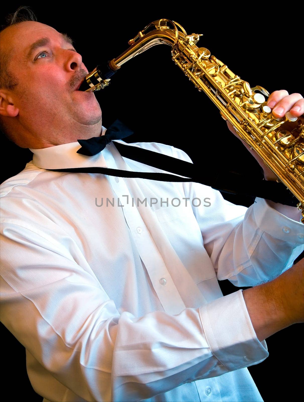 A man is playing alto saxophone on a black background.