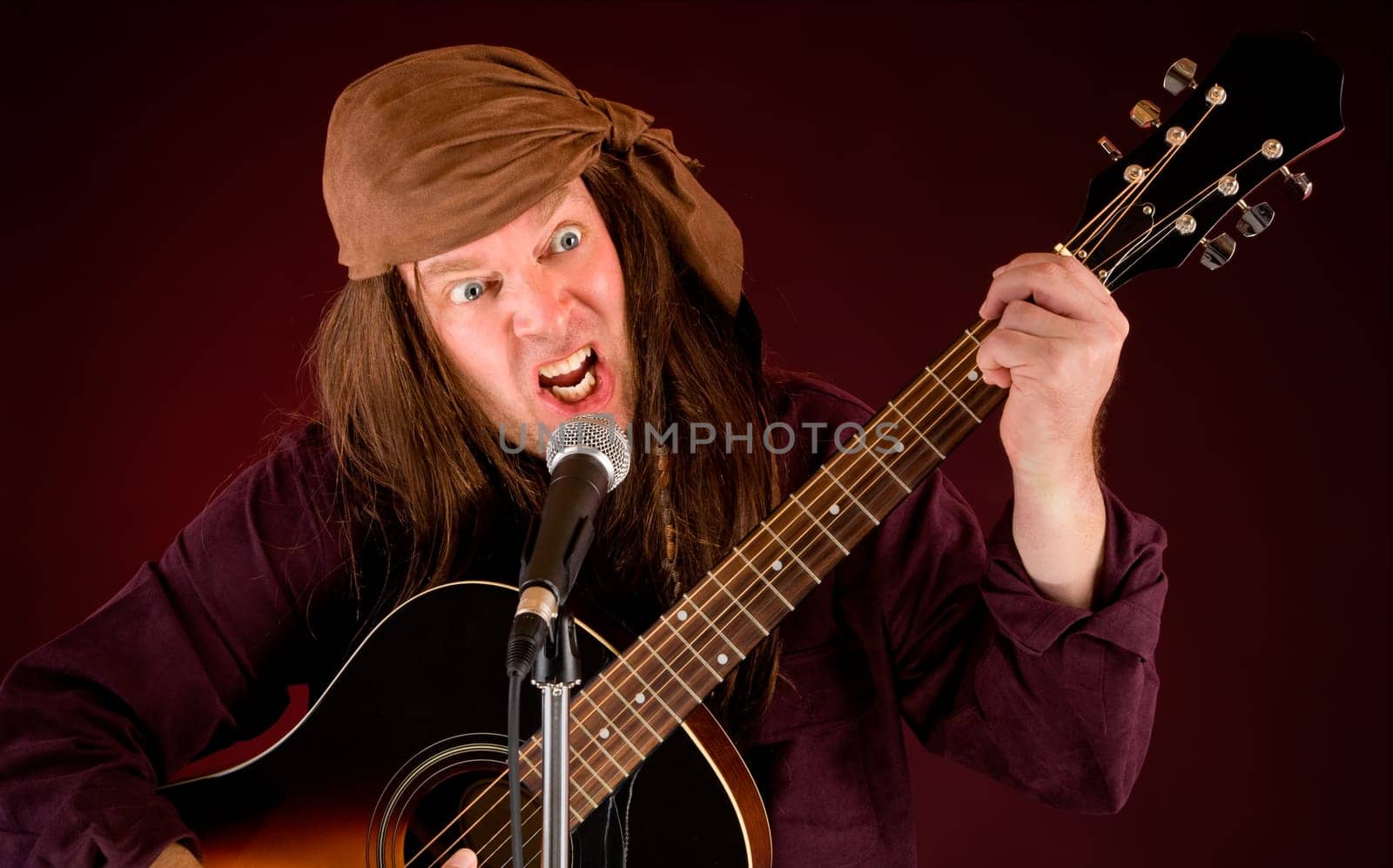A man is madly playing acoustic guitar and singing.