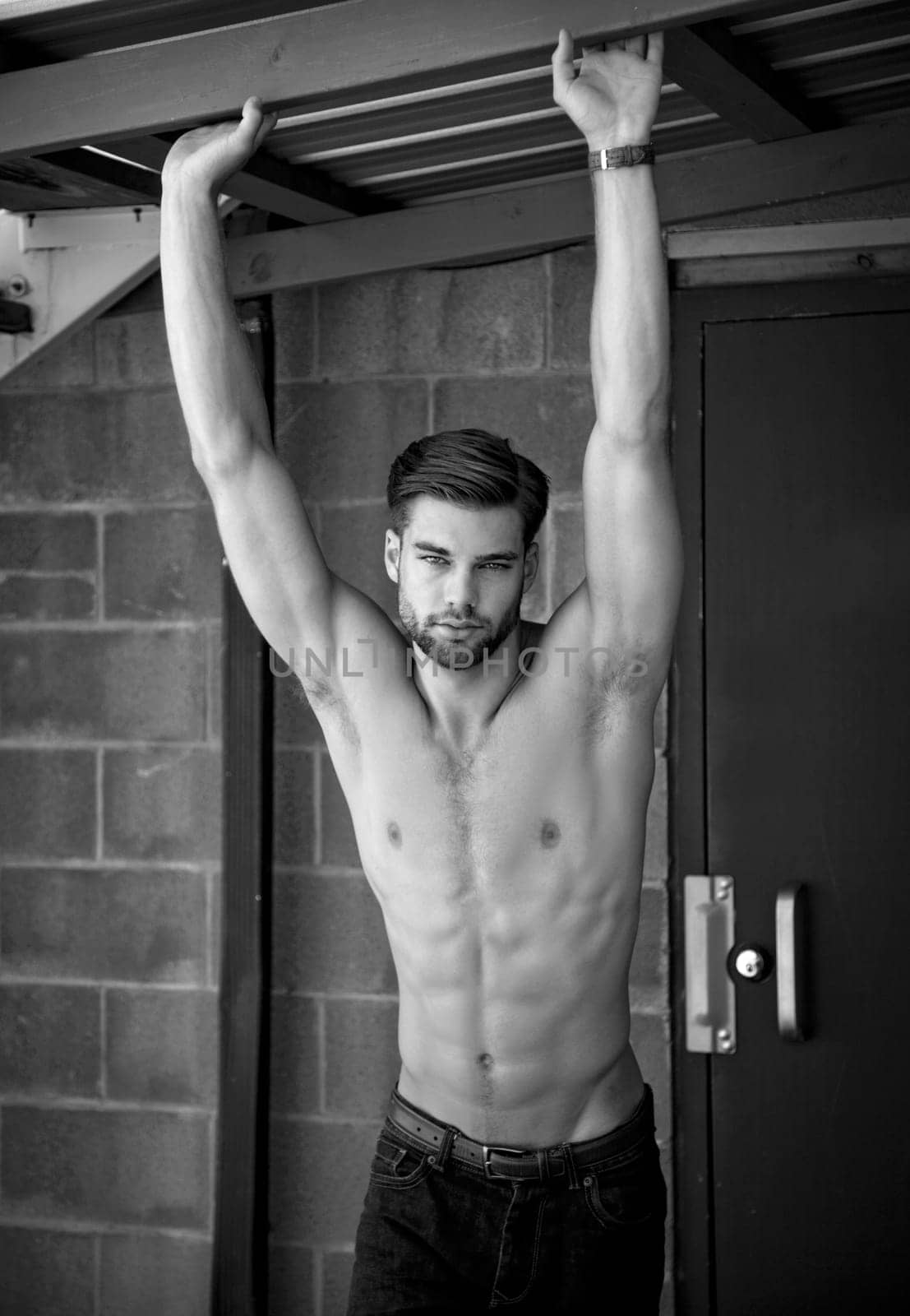 Outdoor photo of shirtless, attractive young man looking at camera.