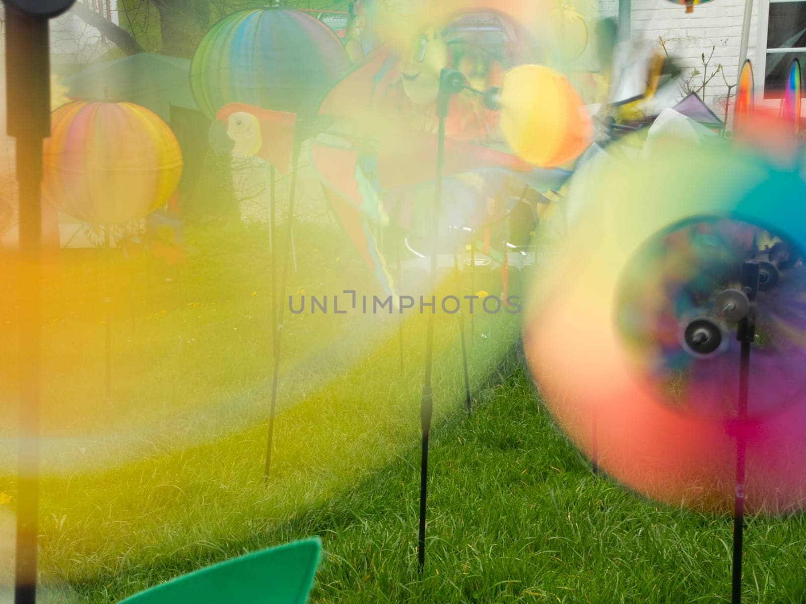 Wide-angle long exposure shot of colorful spinning pinwheels in a meadow.