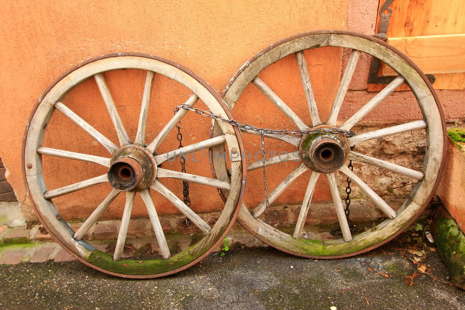 old,wooden wagon wheels leaning against a wall,Alsace,France