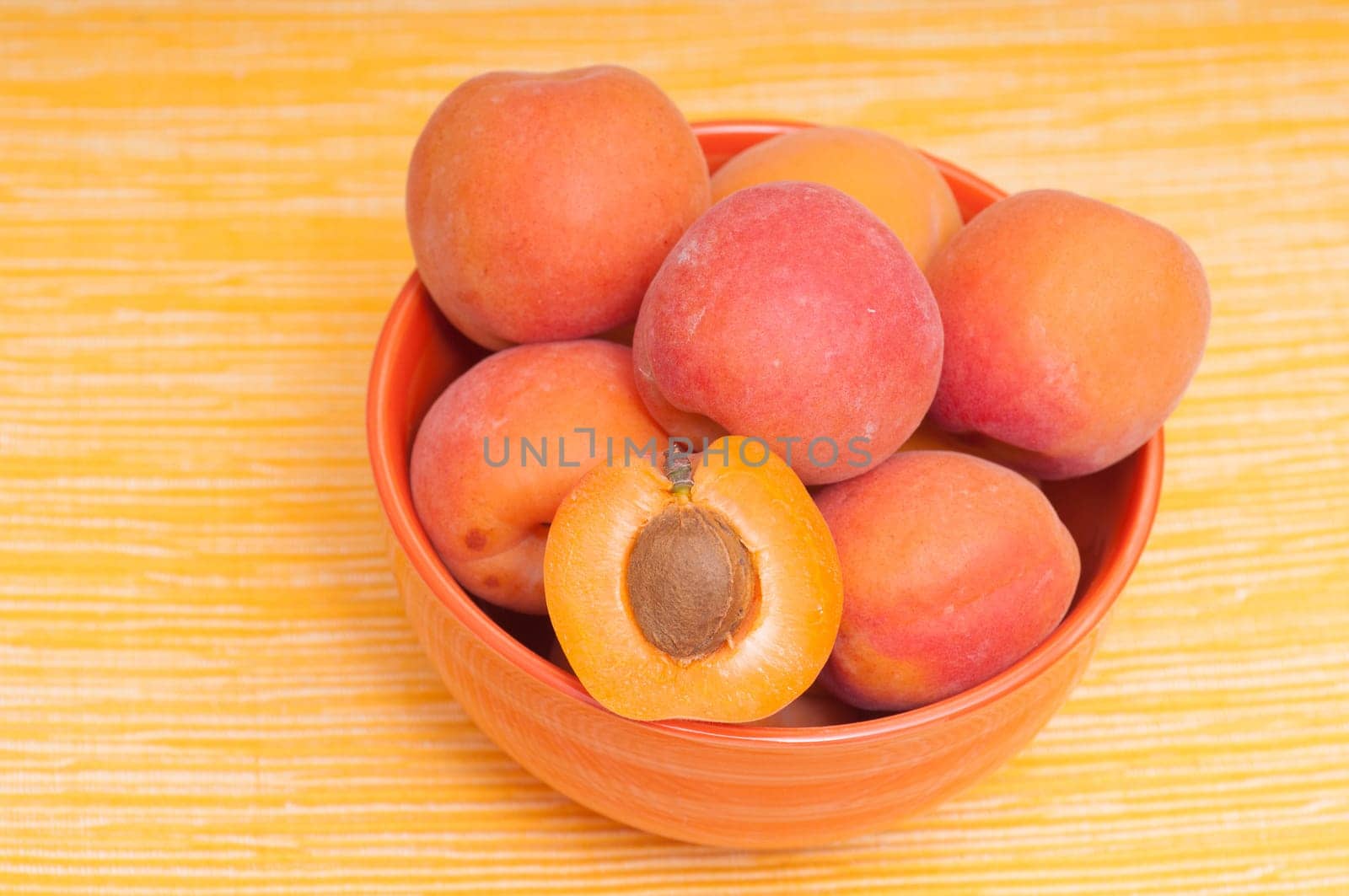 Apricots in a bowl against a yellow background
