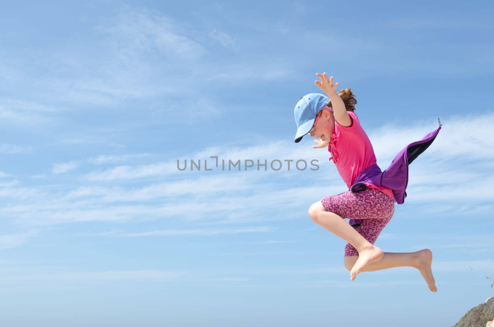 Toddler jumping in front of blue sky