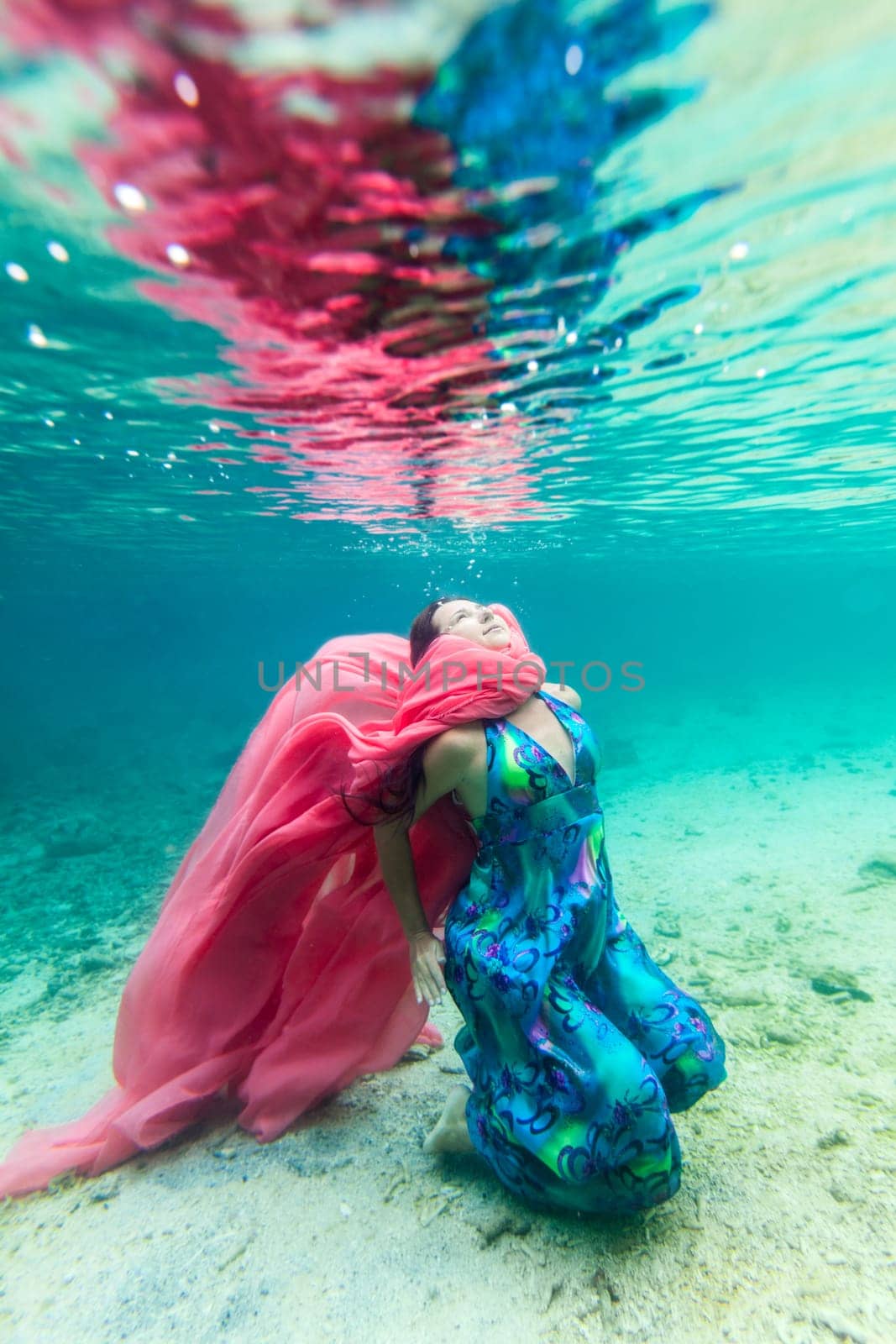 Young beautiful woman in blue dress underwater