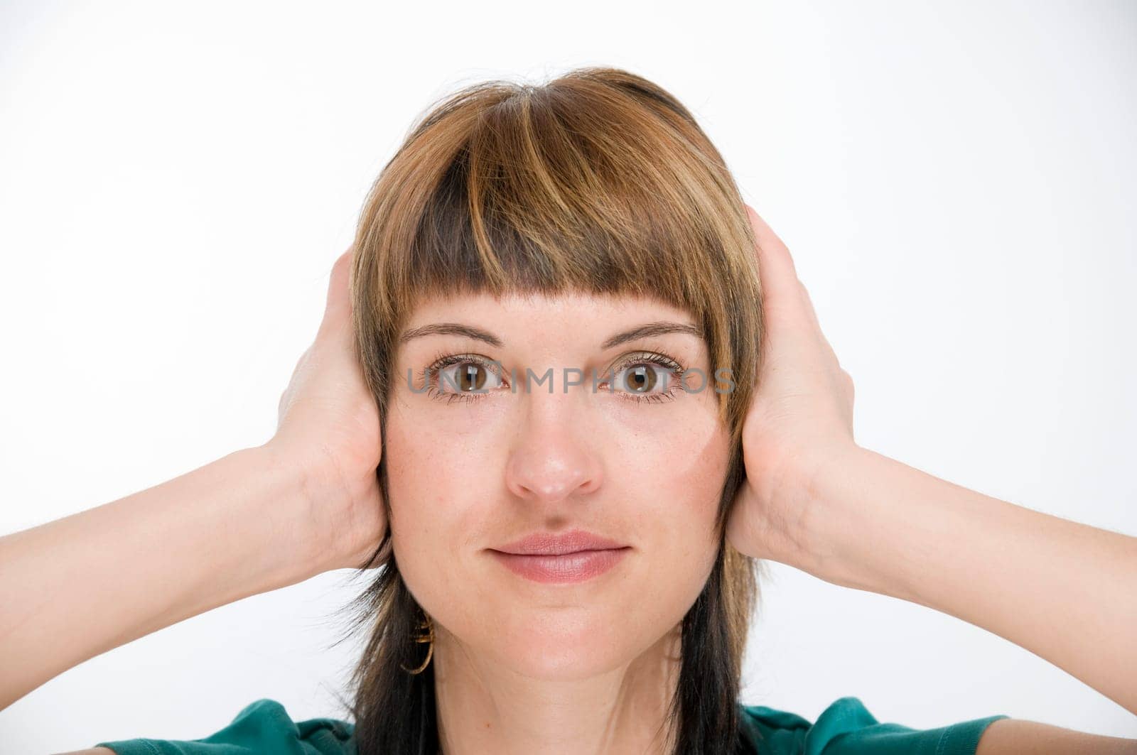 Head and shoulders view of a young woman looking into the camera and covering her ears  Gesture: "hear nothing"""