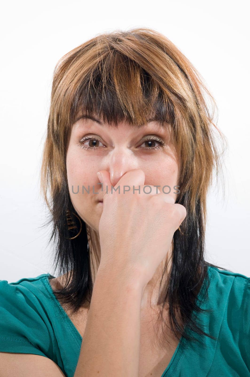 Head and shoulders shot of a young woman looking into the camera,holding her nose