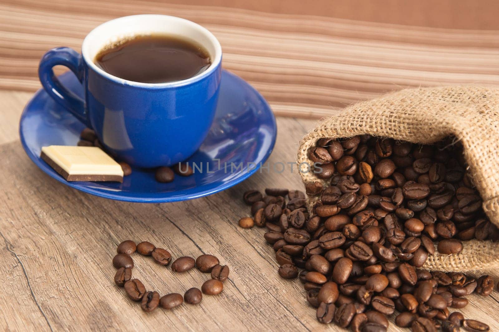 Cup of coffee with beans on old wooden surface