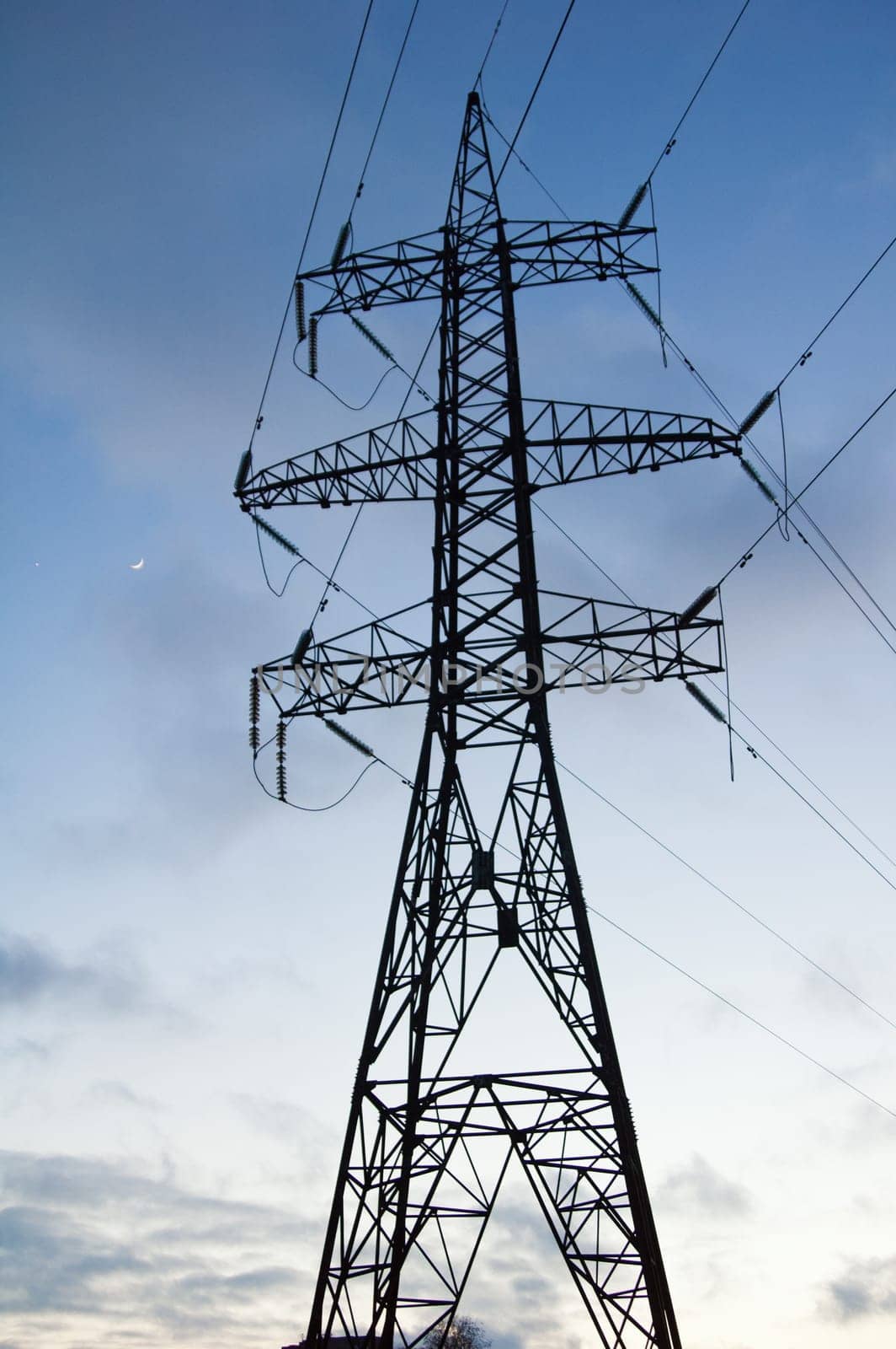 Silhouette of a pillar of electricity transmissions on a background of the evening sky