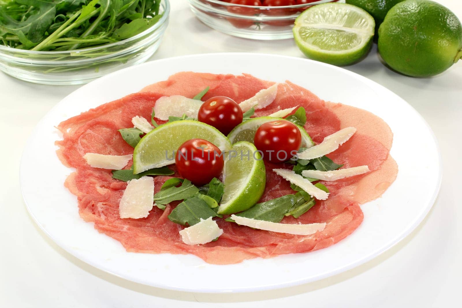 a plate of carpaccio with parmesan,lime and arugula