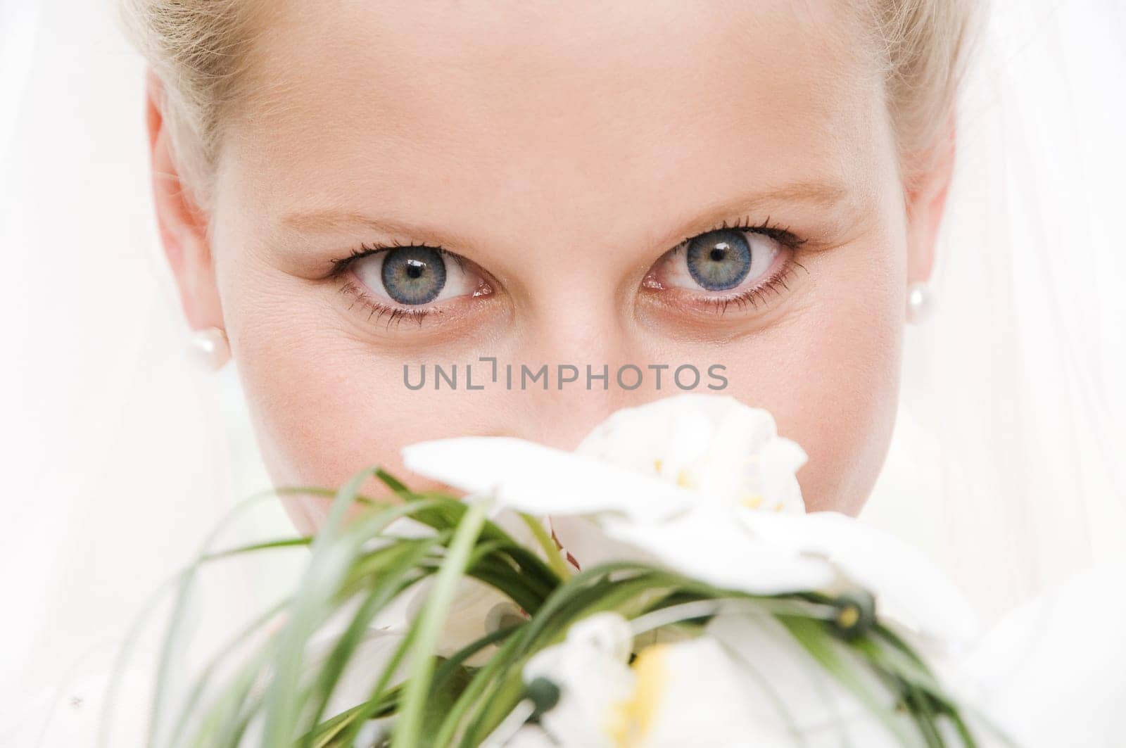 Blonde bride with very beautiful eyes with veil and bridal bouquet