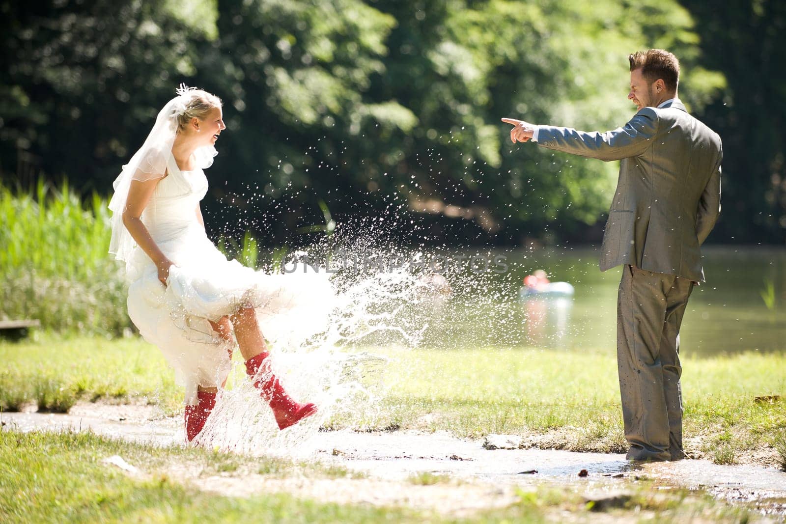Bride and groom in river splashing wet and having fun