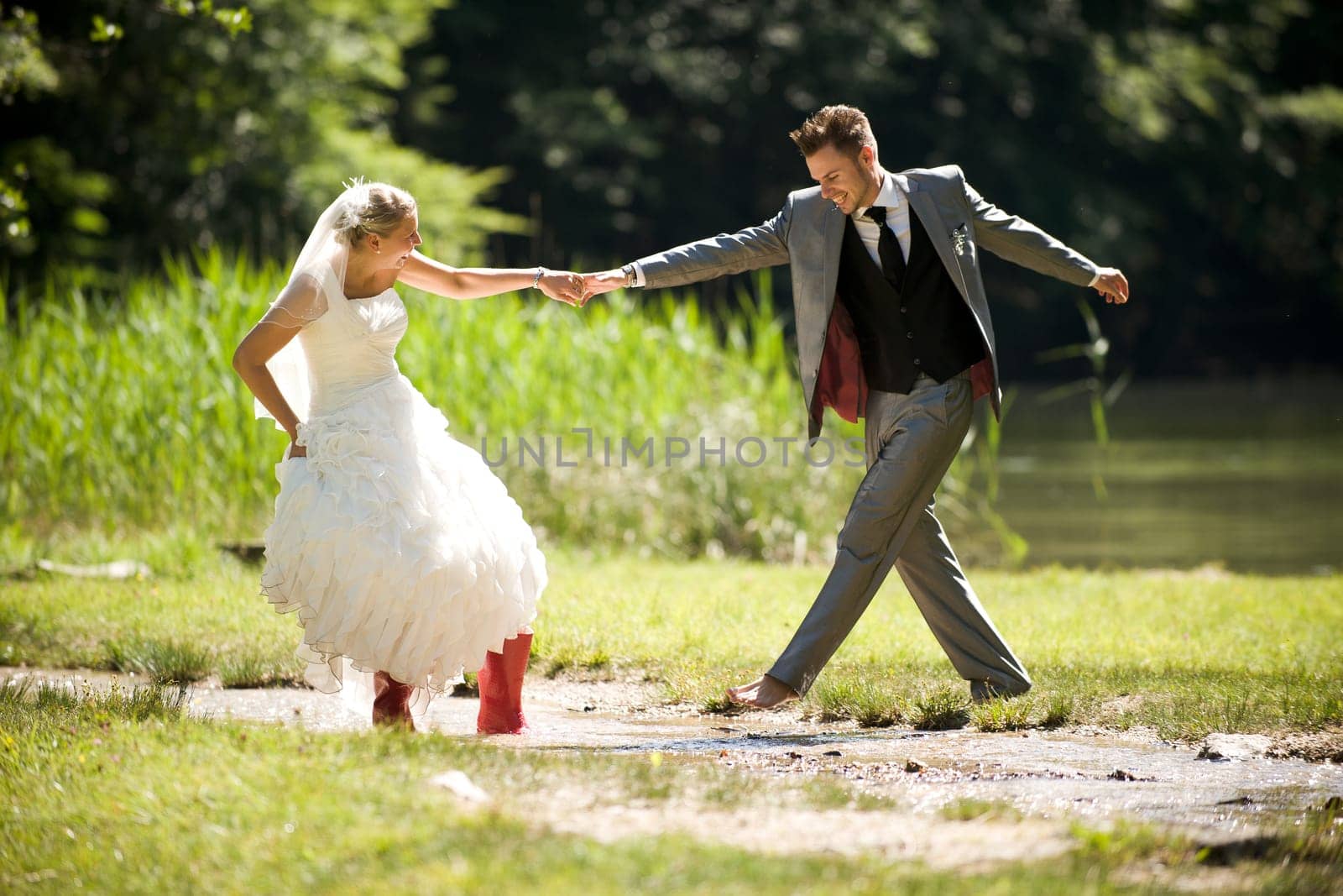 Bride and groom in river splashing wet and having fun