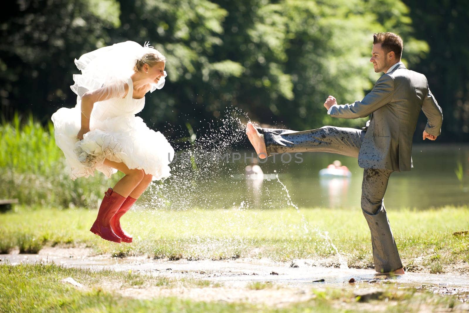 Bride and groom in river splashing wet and having fun