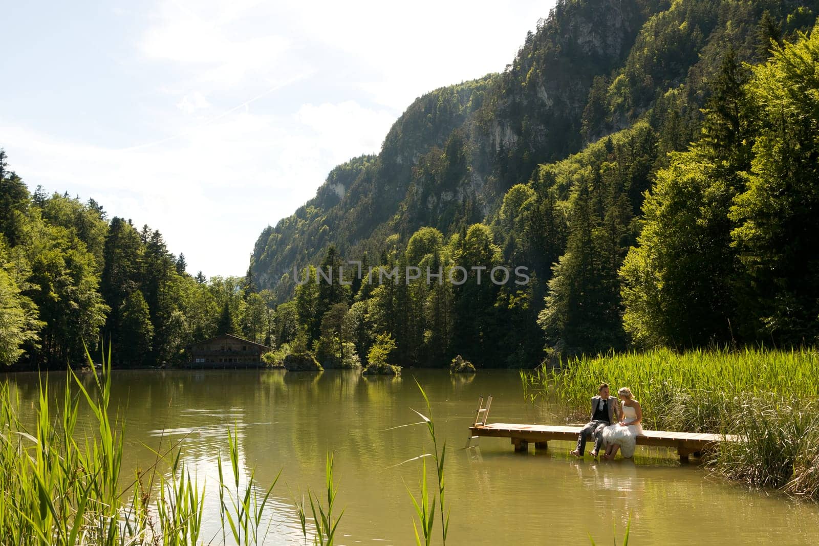 Bride and groom sitting romantically by a lake