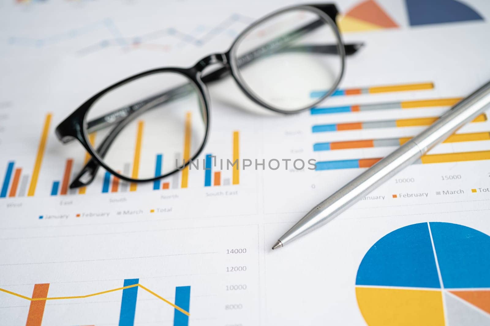 Eyeglass with pen on chart graph paper. Finance, account, statistic, investment data economy, stock exchange business.