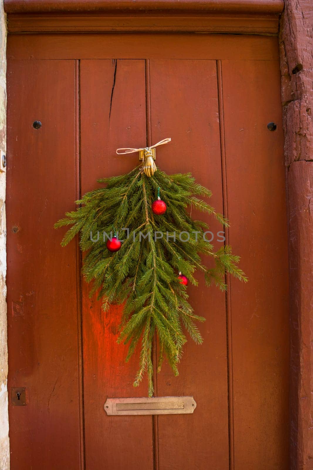 Christmas tree branches and balls decorate the vintage door