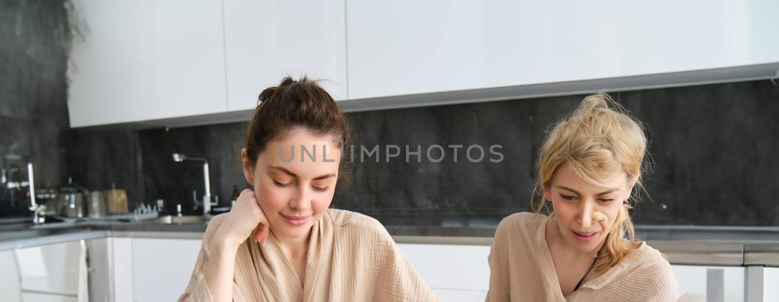 Vertical shot of smiling woman making notes, writing cooking recipe, creates groceries list, sits in the kitchen with vegetables and chopping board.