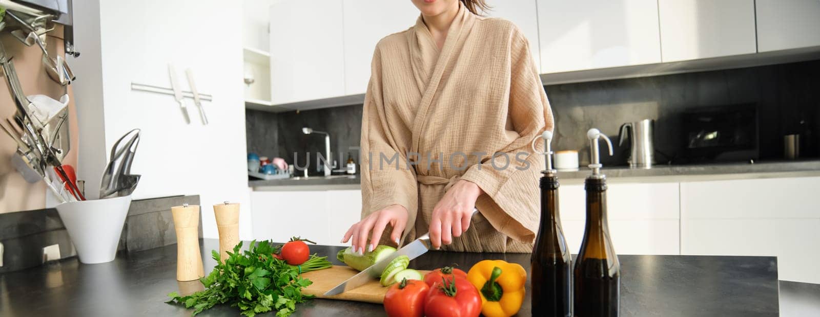 Close up portrait of female hands, woman wearing robe, cutting vegetables on chopping board, cooking vegan dinner, vegetarian meal for family, standing in kitchen.