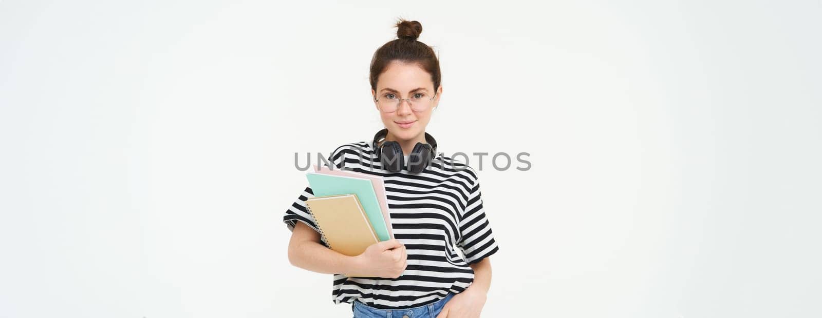 Student lifestyle and people concept. Portrait of young woman in glasses, teacher or college girl with books and study material, posing over white background by Benzoix
