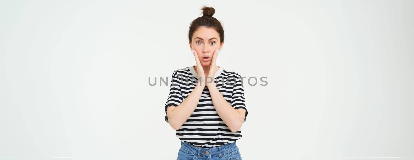 Lifestyle and emotions concept. Portrait of girl with surprised face expression, saying wow, looks impressed at camera, stands over white background.
