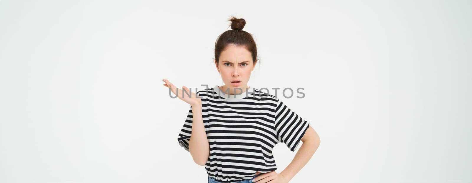 Image of frustrated woman complaining, looking puzzled, shrugging and frowning, standing over white background.